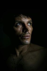 Close-up of man looking away against black background