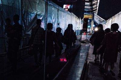 People walking on illuminated street in city at night