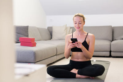 Young woman using mobile phone while sitting on sofa