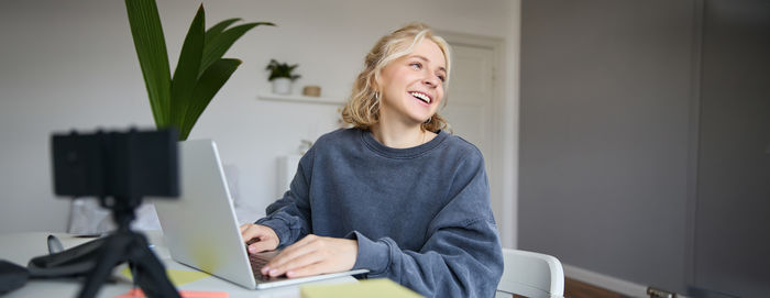 Portrait of young woman using laptop at home