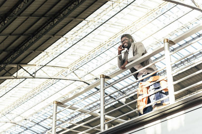 Smiling man talking on mobile phone while standing on bridge