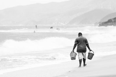 Rear view of men walking on beach