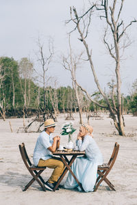 People sitting on seat by trees