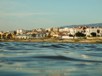 Sea and houses in town against sky