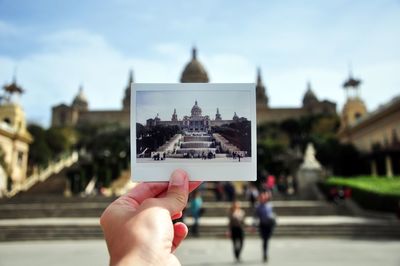 Cropped image of person holding photograph of museu nacional d art de catalunya