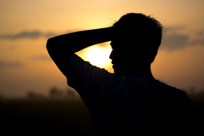 Rear view of silhouette man standing against sky during sunset