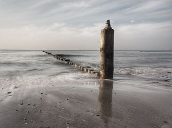 Wooden posts on beach against sky