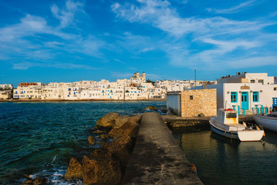 Buildings by sea against blue sky