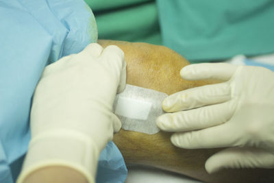 Close-up of surgeon applying bandage on patient leg in operating room