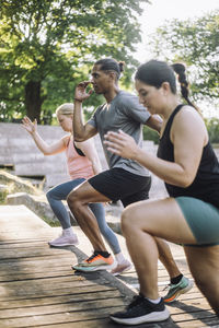 Determined man doing warm up with female friends on steps