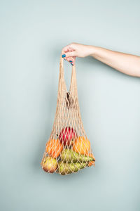 Eco bag with fruit in a woman's hand on a gray background. zero waste. healthy diet