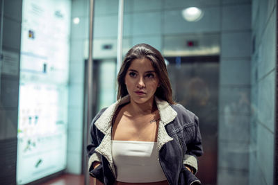 Young woman looking away while standing in corridor