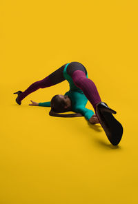 Full length of young woman against yellow background