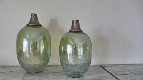 Close-up of empty bottles on table against wall