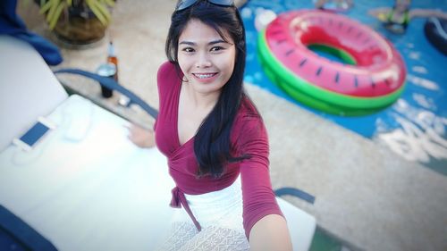 High angle portrait of smiling woman standing on deck chair