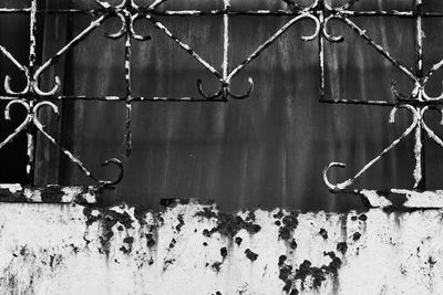 Close-up of rusty metal fence against wall