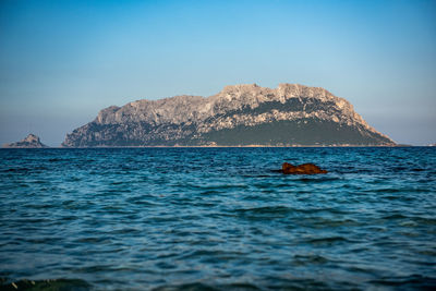 Scenic view of rocks in sea against clear sky