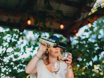 Full length of a woman drinking water from mobile phone