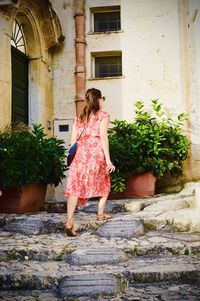 Rear view of woman standing outside house