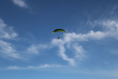 Low angle view of person paragliding against blue sky