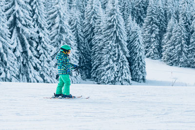 Full length of boy skiing against snow covered trees