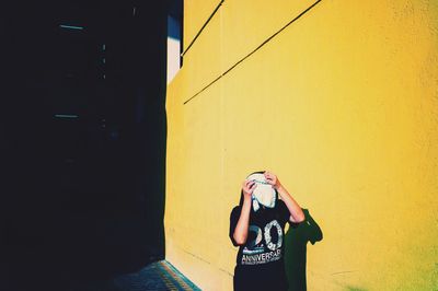 Portrait of young woman standing against wall