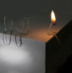 Close-up of paper clips by illuminated matchstick on table