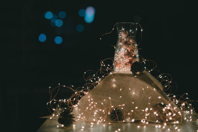 Close-up of illuminated glass jar on table against black background
