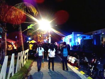 Rear view of people on illuminated city at night