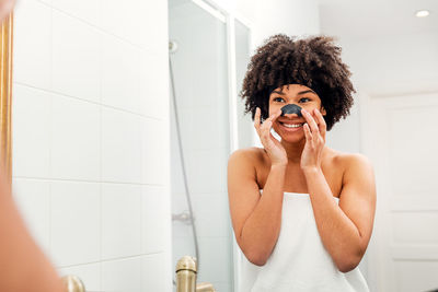 Young woman with arms outstretched standing in bathroom