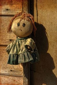 Old doll hanging on wooden door against wall