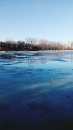 Scenic view of frozen lake against clear blue sky