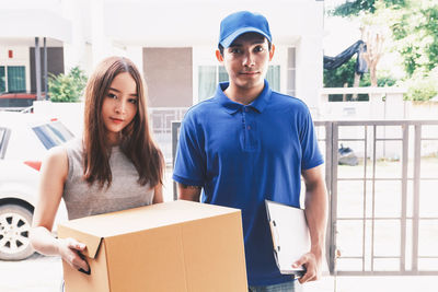 Portrait of woman holding package while standing with salesman