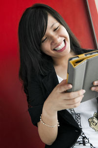 Happy woman using digital tablet against wall