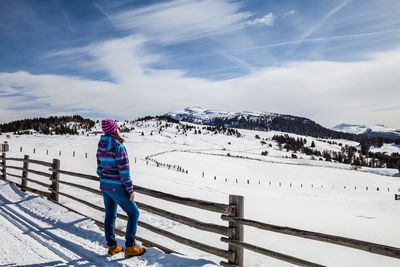 Rear view of person standing on snowcapped mountain against sky