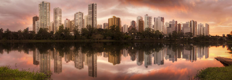 Reflection of trees and buildings in lake against sky