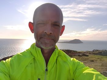 Portrait of smiling man at sea against sky