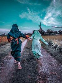 Rear view of women walking on field