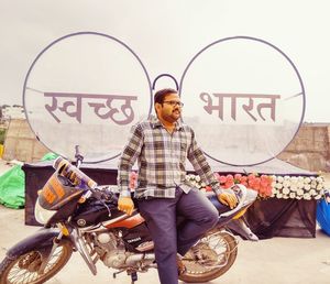 Man standing by bicycle against graffiti wall