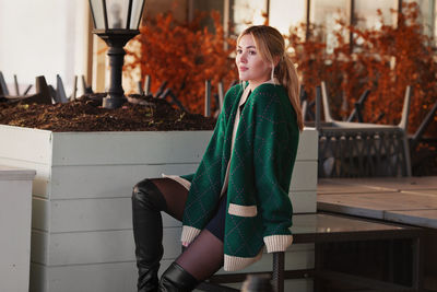 Beautiful woman thinking or waiting. stylish fashion model wearing oversize green sweater, shorts