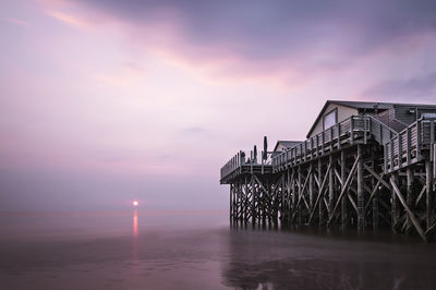 Pier over sea against sky during sunset