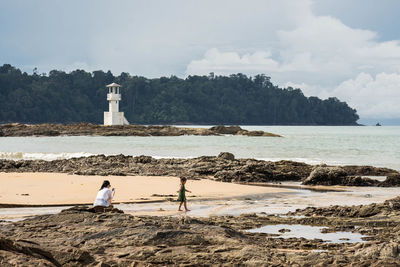 People on beach by sea against sky