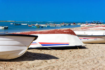 Deck chairs on beach against clear blue sky