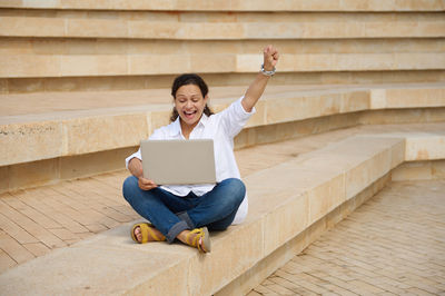 Side view of woman using mobile phone while sitting on steps