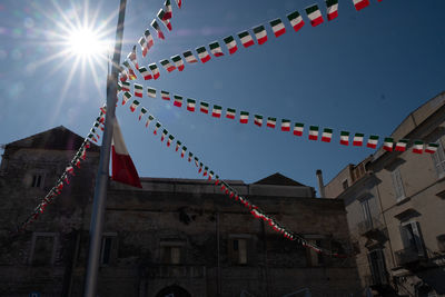 Low angle view of flags hanging on building against sky