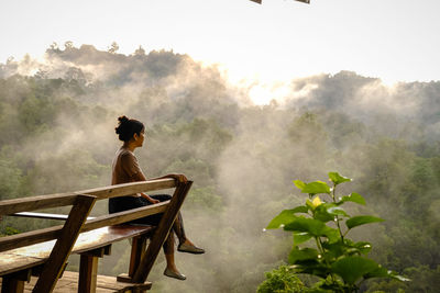 Side view of woman standing by plants against sky