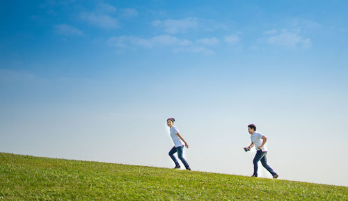 Side view of people on field against sky