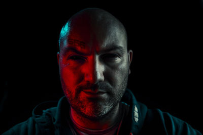 Close-up portrait of serious man against black background