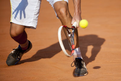 Low section of man playing tennis at court