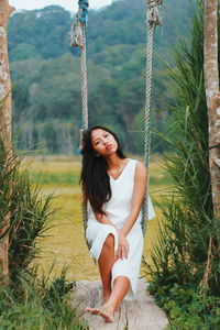 Portrait of smiling young woman sitting on swing